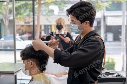 Preview: Beauty salon Asian barber man with hygiene mask use scissors cut hair of customer