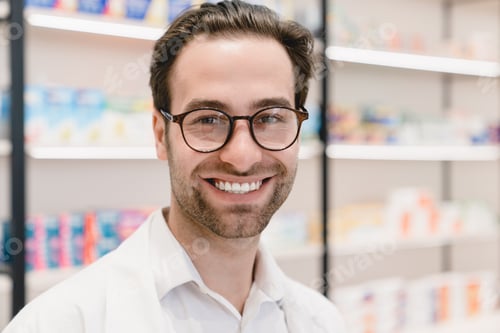 Preview: Pharmacist druggist in white medical coat looking at camera in pharmacy drugstore