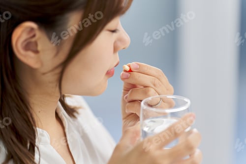 Preview: Asian woman drinking capsule medicine