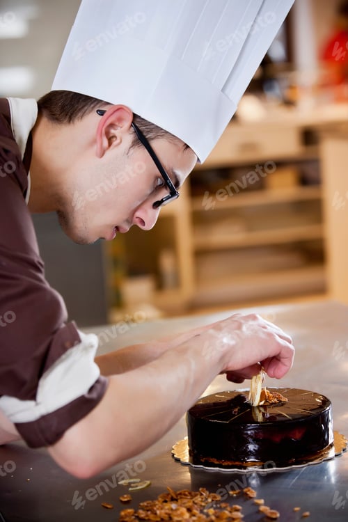 Preview: Baker decorating cake in kitchen