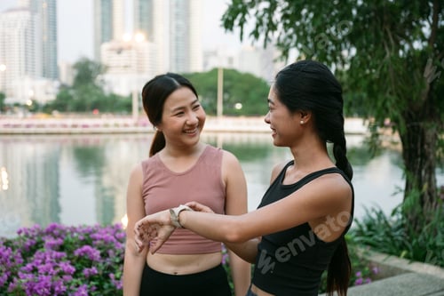 Preview: Two young women checking smartwatch after training in bangkok park