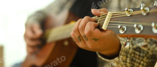 Preview: Close up of musician playing acoustic guitar at home