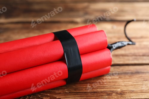 Preview: Red explosive dynamite bomb on wooden background, closeup