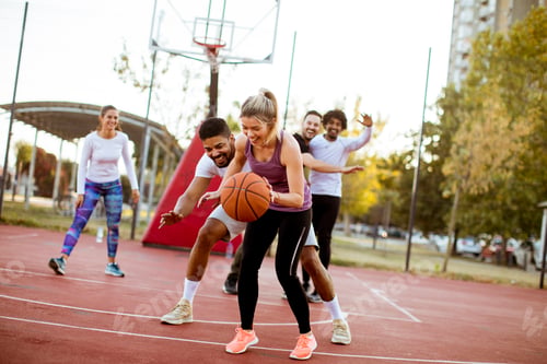 Preview: Group of multiracial young people playing basketball outdoors