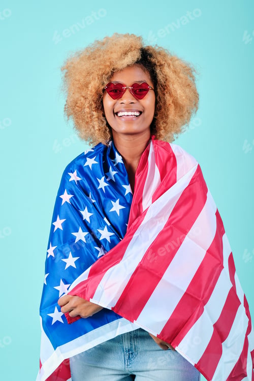 Preview: Portrait of an afro woman smiling while wrapped with an USA flag.