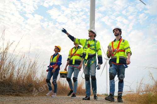 Preview: Wide perspective of wind turbine engineers walking with coworker in wind farms
