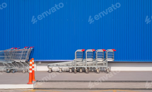 Preview: Row of shopping carts in front of blue aluminium corrugated metal wall of modern hypermarket