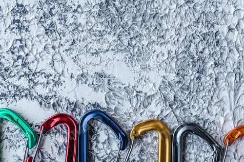 Preview: Isolated photo of climbing equipment. Part of carabiner lying on the white and grey colored surface