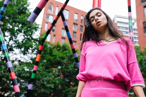 Preview: Young stylish woman posing under colorful urban installation