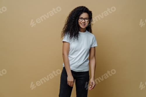 Preview: Smiling dark skinned young woman with glad face expression, wears optical glasses