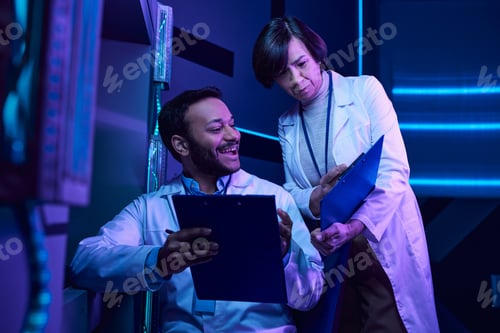 Preview: Hindu Male and Adult Female Scientists Analyze Data and Share Smiles in Neon-Lit Science Center