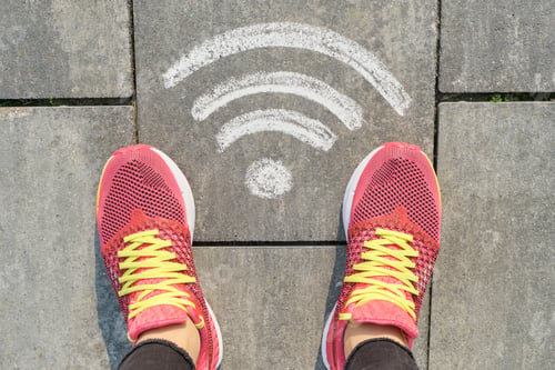 Preview: Wi-fi symbol on gray sidewalk with woman legs in sneakers, top view