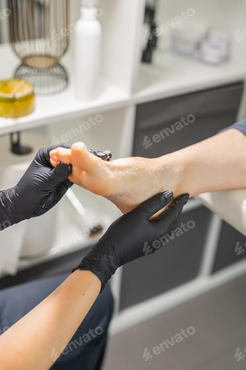 Preview: Woman doing foot peeling in pedicure SPA salon. Sugar scrub and relax beauty procedure