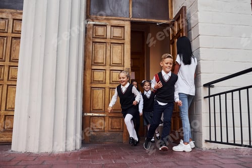 Preview: Group of kids in school uniform running out from a building through the door