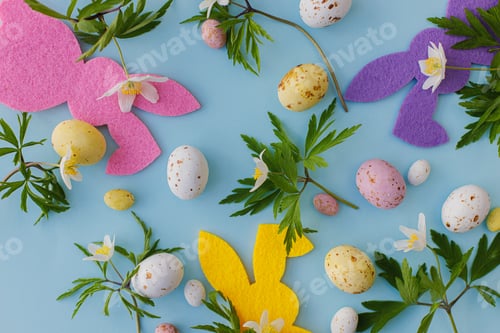 Preview: Colorful Easter bunnies, chocolate eggs and spring flowers flat lay on blue. Happy Easter