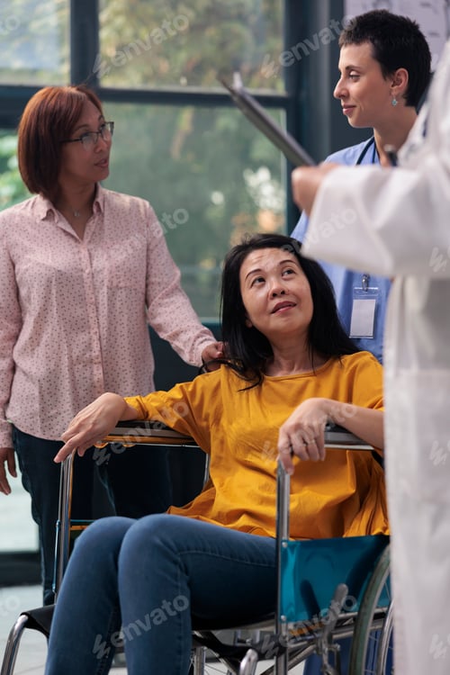 Preview: Senior physician talking to wheelchair user and consulting injured patient