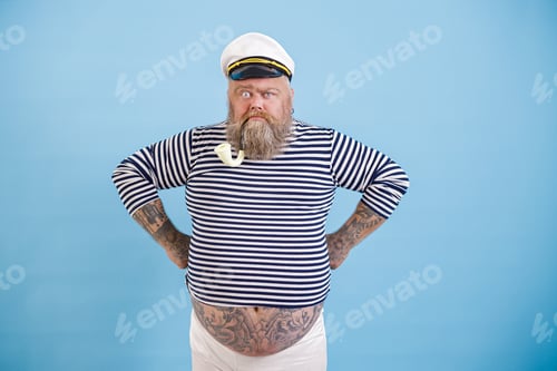 Preview: Funny bearded fat man in sailor suit with smoking pipe on light blue background