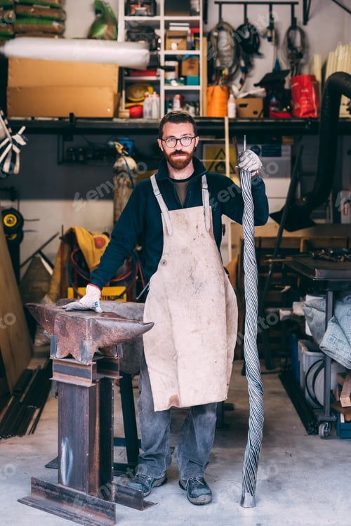 Preview: Portrait of metalworker leaning on anvil in forge workshop