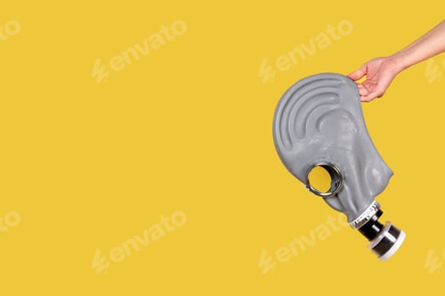 Preview: Hand holding gas mask on yellow background