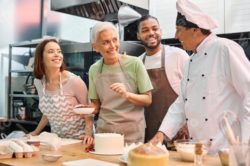 Preview: joyous multiracial students smiling at chef while decorating delicious cake, cooking courses
