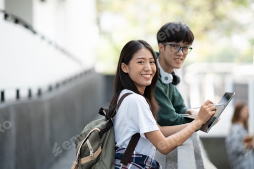 Preview: Young male and female college student standing together while discussing on the project in front of