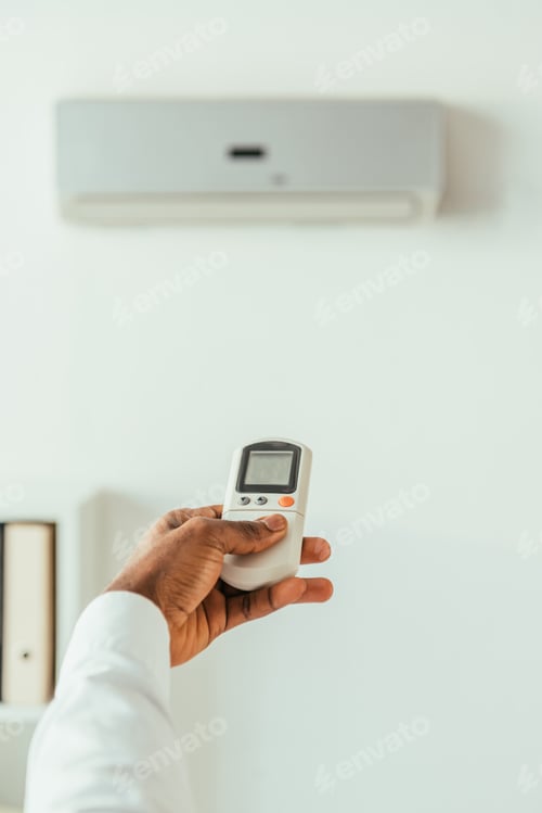 Preview: cropped view of african american businessman holding remote controller while standing under air