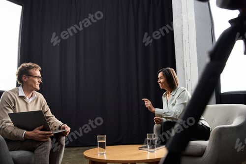 Preview: Middle-aged female journalist conducts an engaging interview with a professional man indoors