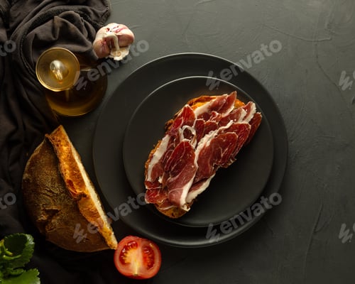 Preview: Delicious iberian ham toast with rustic bread and olive oil on black plate