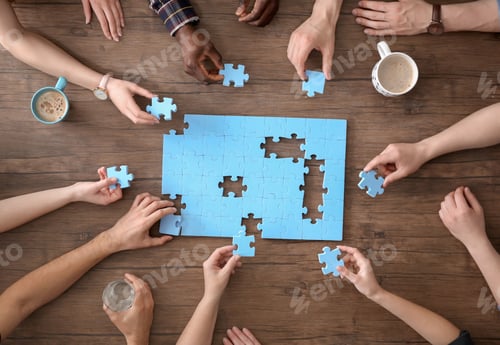 Preview: People with puzzle on wooden background, closeup of hands. Unity concept