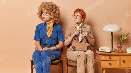 Preview: Indoor shot of serious young women from past dressed in elegant clothes concentrated attentively