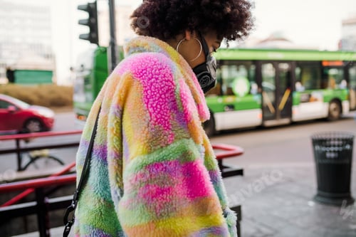 Preview: Young woman walking outdoor in Milan wearing medical mask protecting from pollution and virus