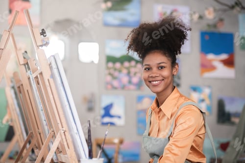 Preview: A young black artist paints acrylic paints on canvas with determination in her painting studio