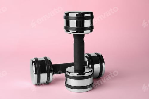 Preview: Dumbbells on light pink background. Weight training equipment