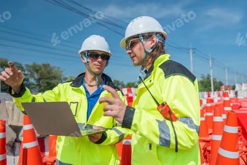 Preview: Two engineers in high visibility jackets and helmets discussing construction details