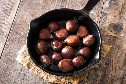 Preview: Chestnuts roasting in a cast iron pan on rustic wooden table