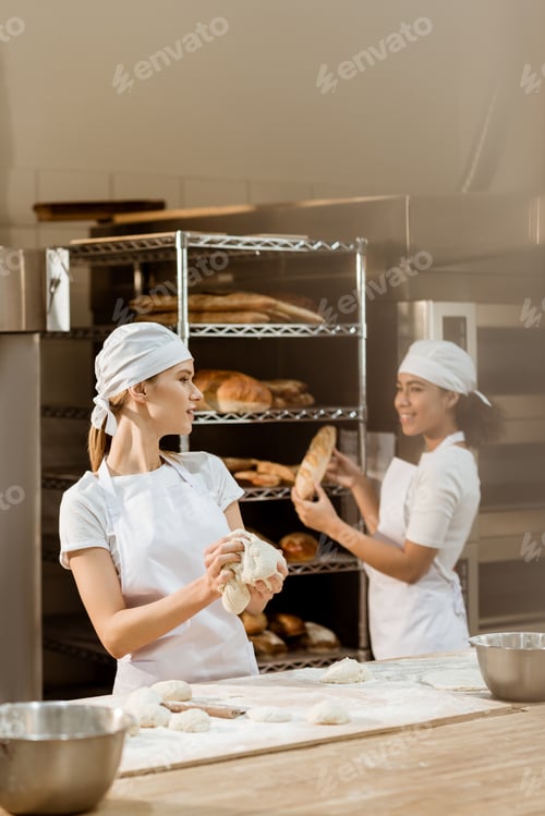 Preview: young female bakers working together at baking manufacture