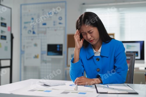 Preview: Stressed asian businesswoman having headache while working in office