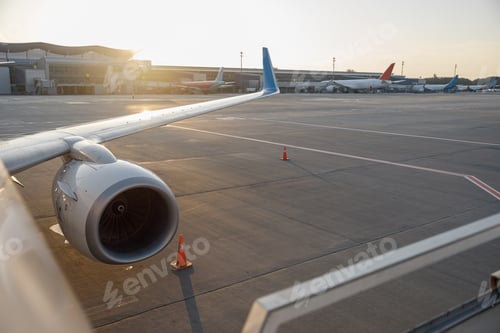 Preview: Close up shot of a wing of commercial airplane near the terminal in an airport at the sunset