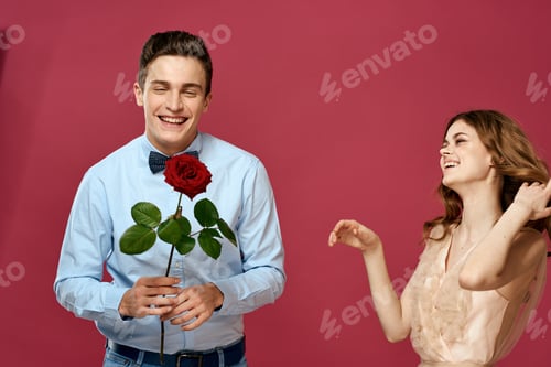 Preview: enamored man and woman with a red flower on a pink background hug each other Copy Space
