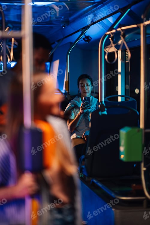 Preview: Young woman using smartphone on night bus ride home