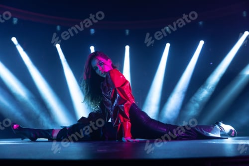 Preview: Young cool female performer doing a split on an illuminated stage