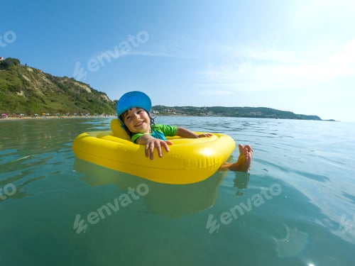 Preview: Adorable baby girl swimming in the sea in a rubber ring