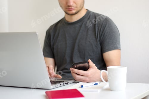 Preview: Young man sitting at the table using laptop