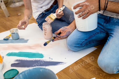 Preview: Young couple sitting on the floor choosing color for painting the wall in their home.