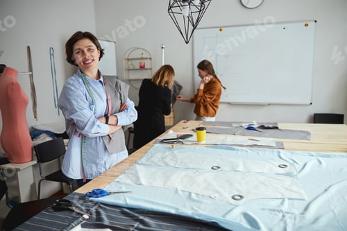 Preview: Proud woman standing next to a fabric peice during dressmaking