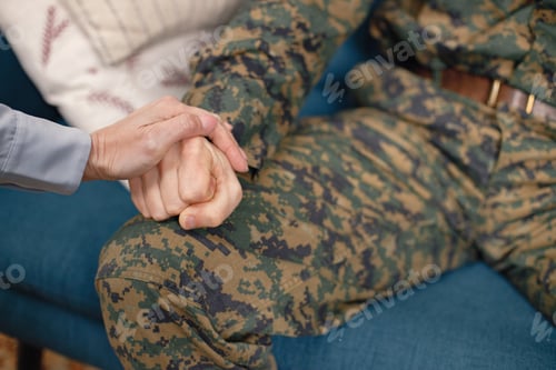 Preview: Cropped shot of a hand's of young soldier sitting on a sofa and woman
