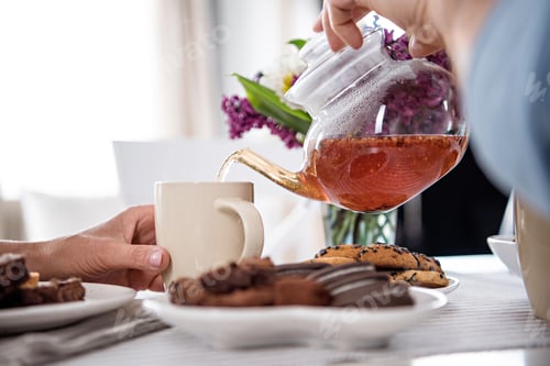 Preview: cropped shot of man pouring tea into cup during breakfast at home