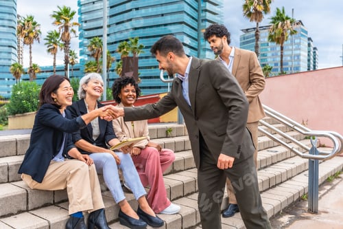 Preview: Businessman hand shaking hands with three multi-ethnic businesswoman outdoors