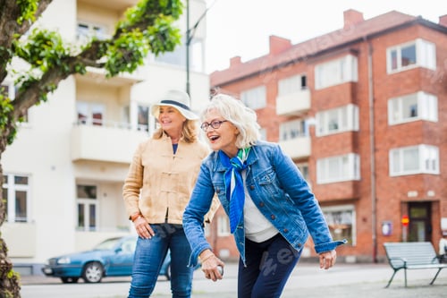 Preview: Two joyful women sharing a laughter on a city street.
