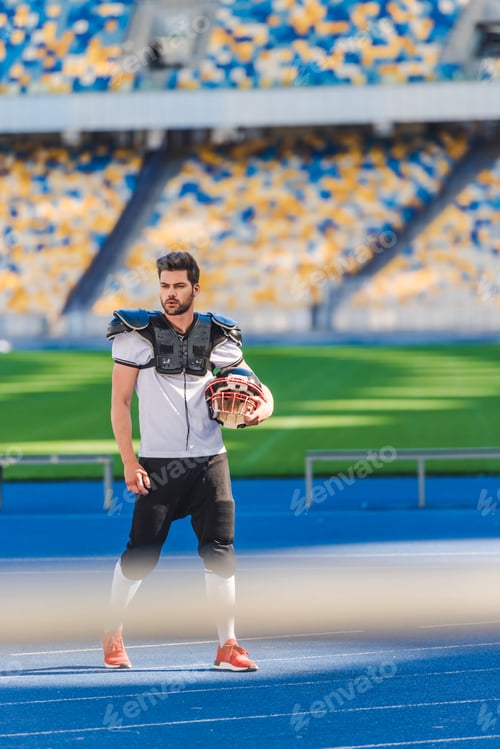 Preview: handsome young american football player standing alone at sports stadium
